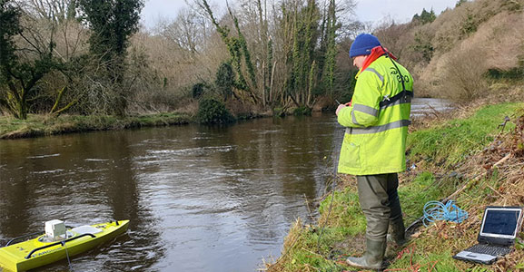 Boat on river, man on river bank with yellow coat